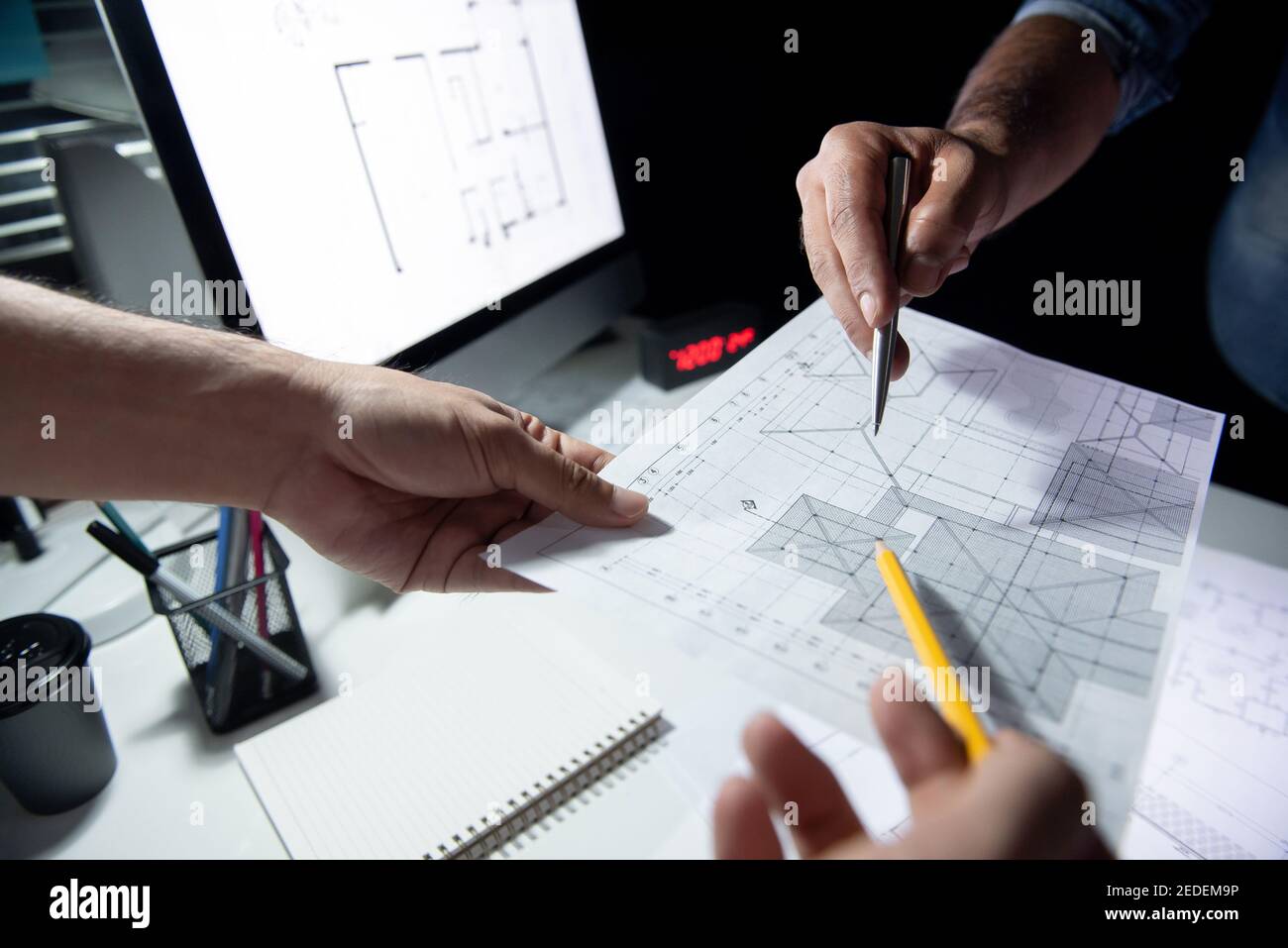 Architekten- oder Ingenieurteam, das das Projekt auf einem Blueprint in diskutiert Dunkles Büro spät in der Nacht Stockfoto