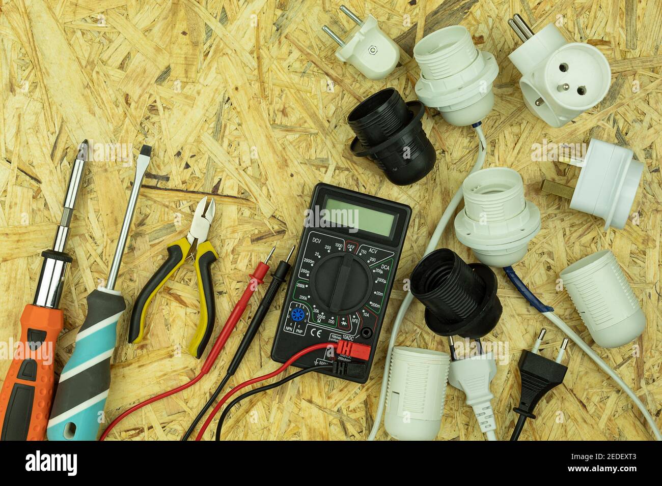 Installation der elektrischen Verdrahtung und Anschluss von Steckdosen und Steckern an Drähte. Elektrische Gegenstände und Werkzeuge werden mit leeren sp. Auf dem Tisch verteilt Stockfoto