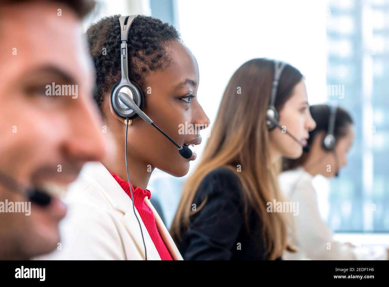 Afroamerikanische Frau Telemarketing Kundenservice Mitarbeiter arbeiten mit verschiedenen Team im Callcenter Stockfoto