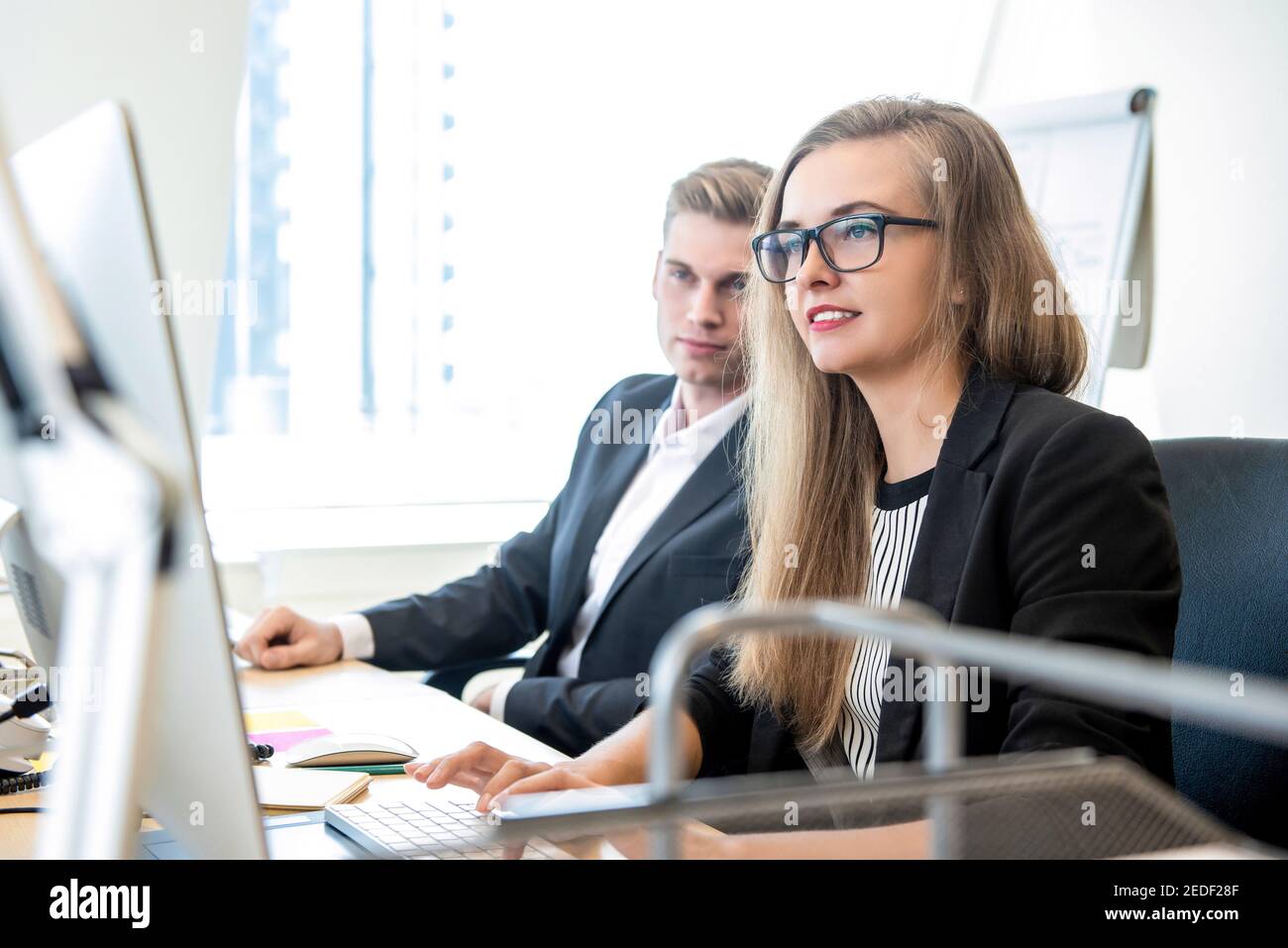 Schöne Geschäftsfrau arbeiten am Computer im Büro mit männlich Mitarbeiter Stockfoto