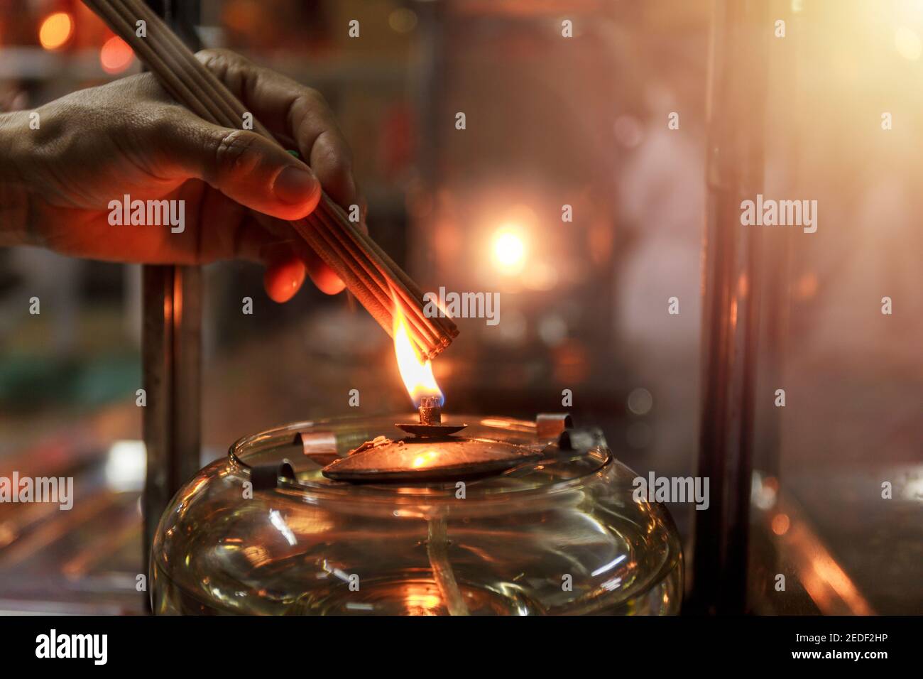 Nahaufnahme Hand cense joss Stick mit Öl Lampe Feuer. Mit Folienkorneffekt Stockfoto