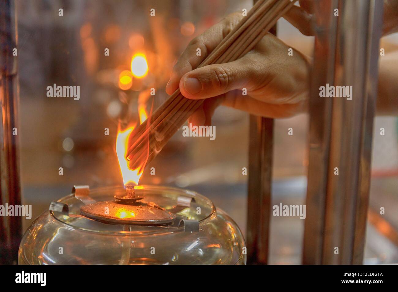Nahaufnahme Hand cense joss Stick mit Öl Lampe Feuer. Mit Folienkorneffekt Stockfoto