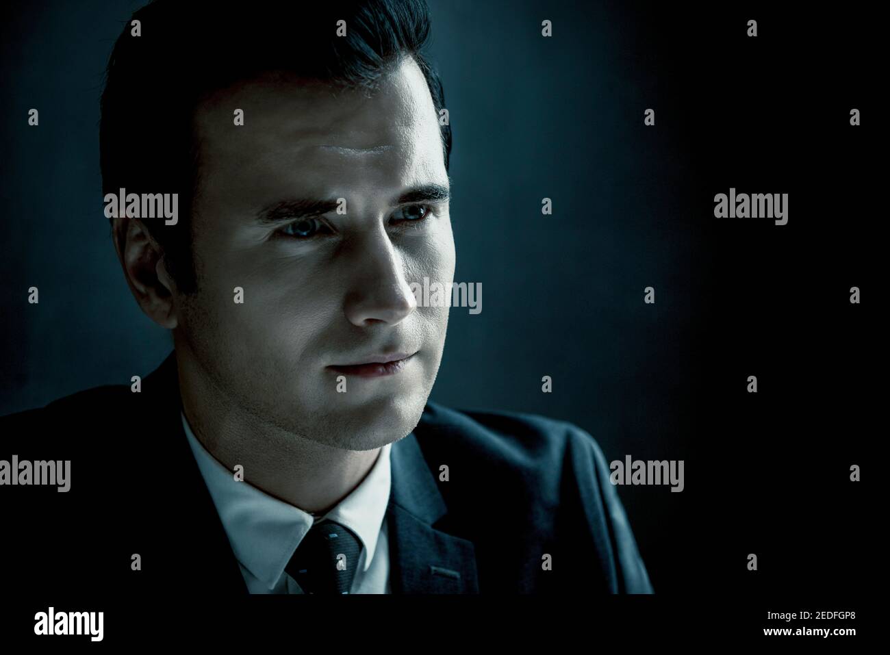 Mann im Schatten mit ernsthafteren Gesicht als Polizeidetektiv Im dunklen Verhörraum Stockfoto