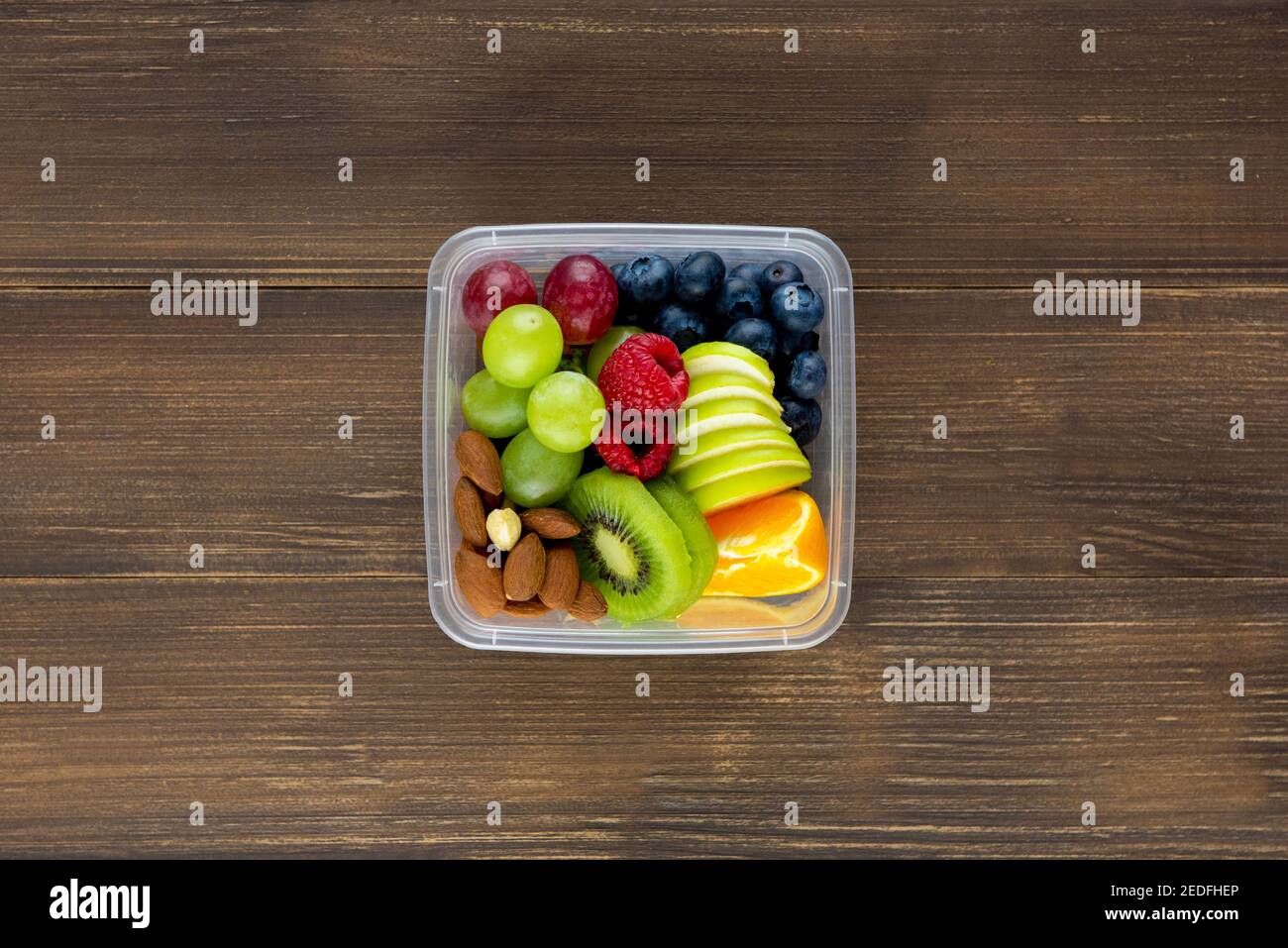 Bunte frische gesunde Mischfrüchte mit Mandeln in der Take-away-Box Auf Holztisch Blick von oben Stockfoto