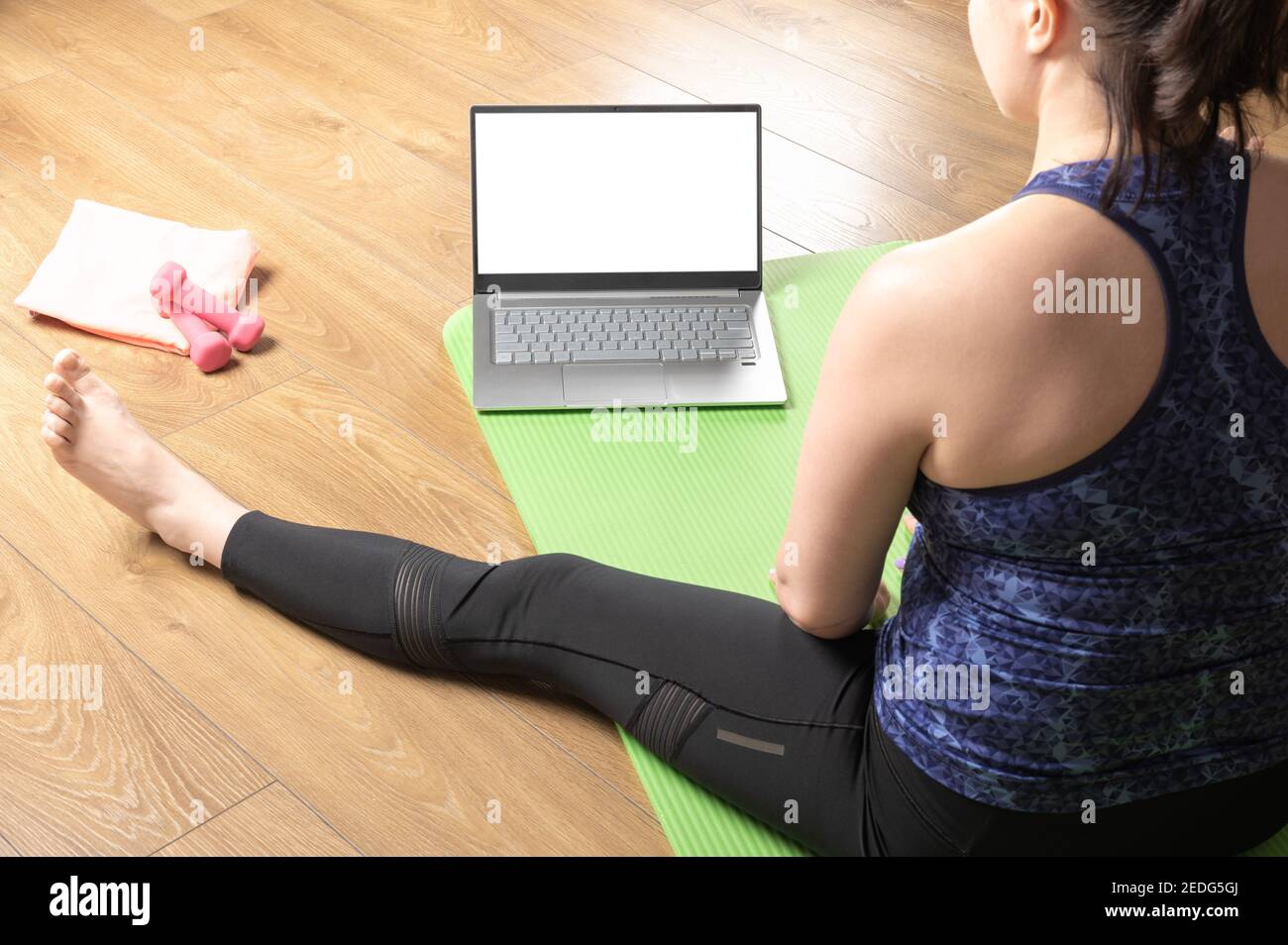 Fitnesstraining online, Rückansicht über Schulter bei 40s Frauen mittleren Alters zu Hause mit Laptop. Online Laptop Yoga Home Fitness Workout. Sportlich Stockfoto