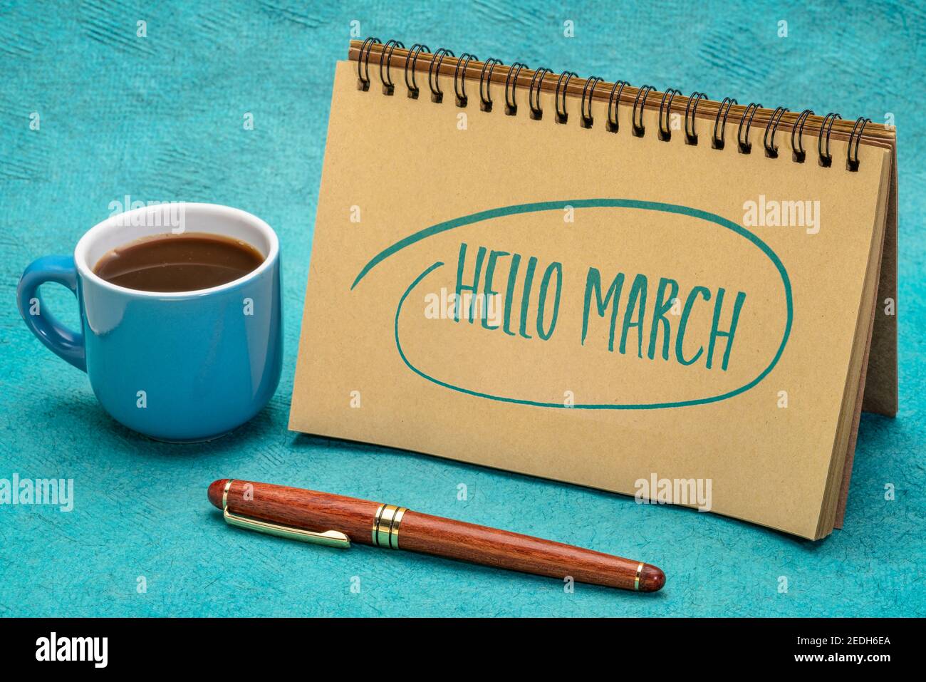Hallo März! Handschrift in einem Spiralheft mit einer Tasse Kaffee und einem Stift. Stockfoto