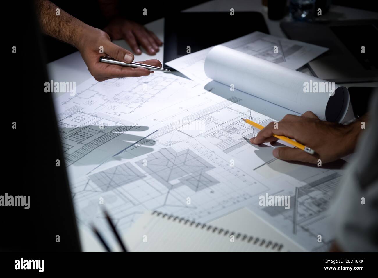 Architektenteam diskutiert Projekt mit Grundriss Blaupause Papier auf Der Tisch im Büro in der Nacht Stockfoto