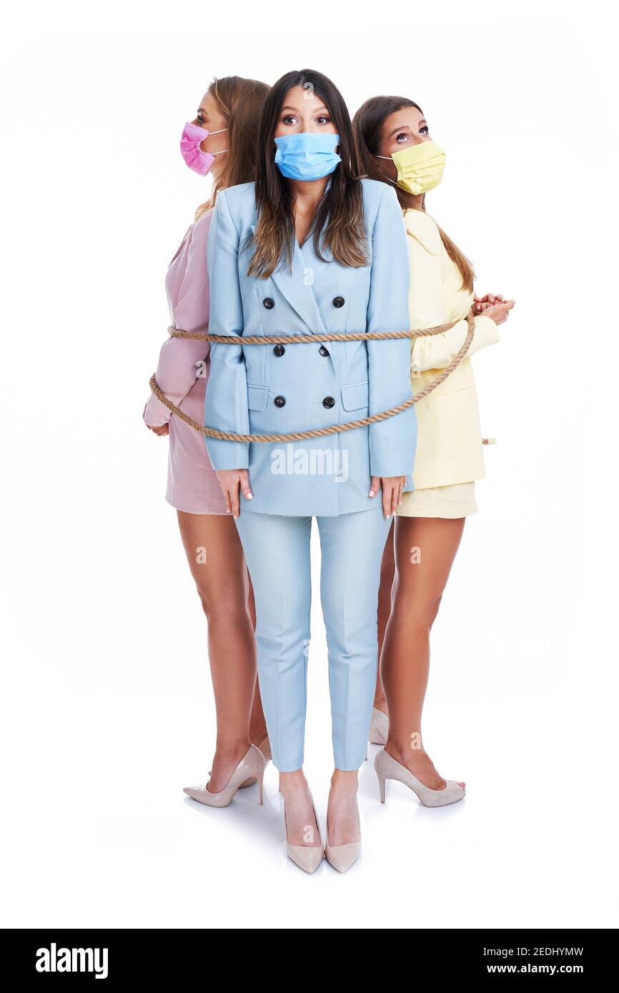 Drei Frauen in Pastellanzügen mit Seil über posiert gehemmt Weißer Hintergrund Stockfoto