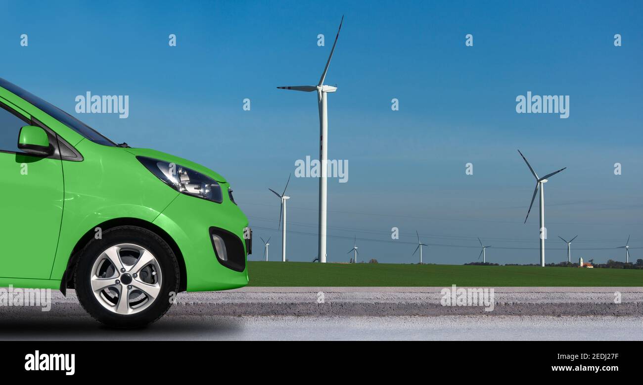 Grünes Elektroauto auf einem Hintergrund von Windkraftanlagen Stockfoto
