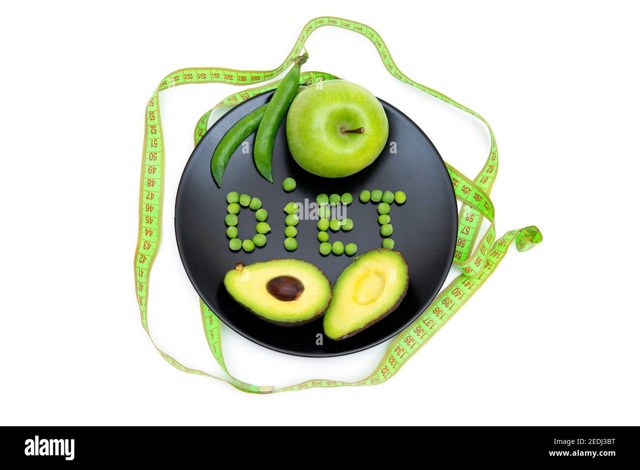 Kreative flache Lay-Komposition aus einem ganzen grünen Apfel, Schnitt Avocado und weiches Maßband auf einem schwarzen Teller mit einem Wort ERNÄHRUNG aus frischen Gartenerbsen Stockfoto