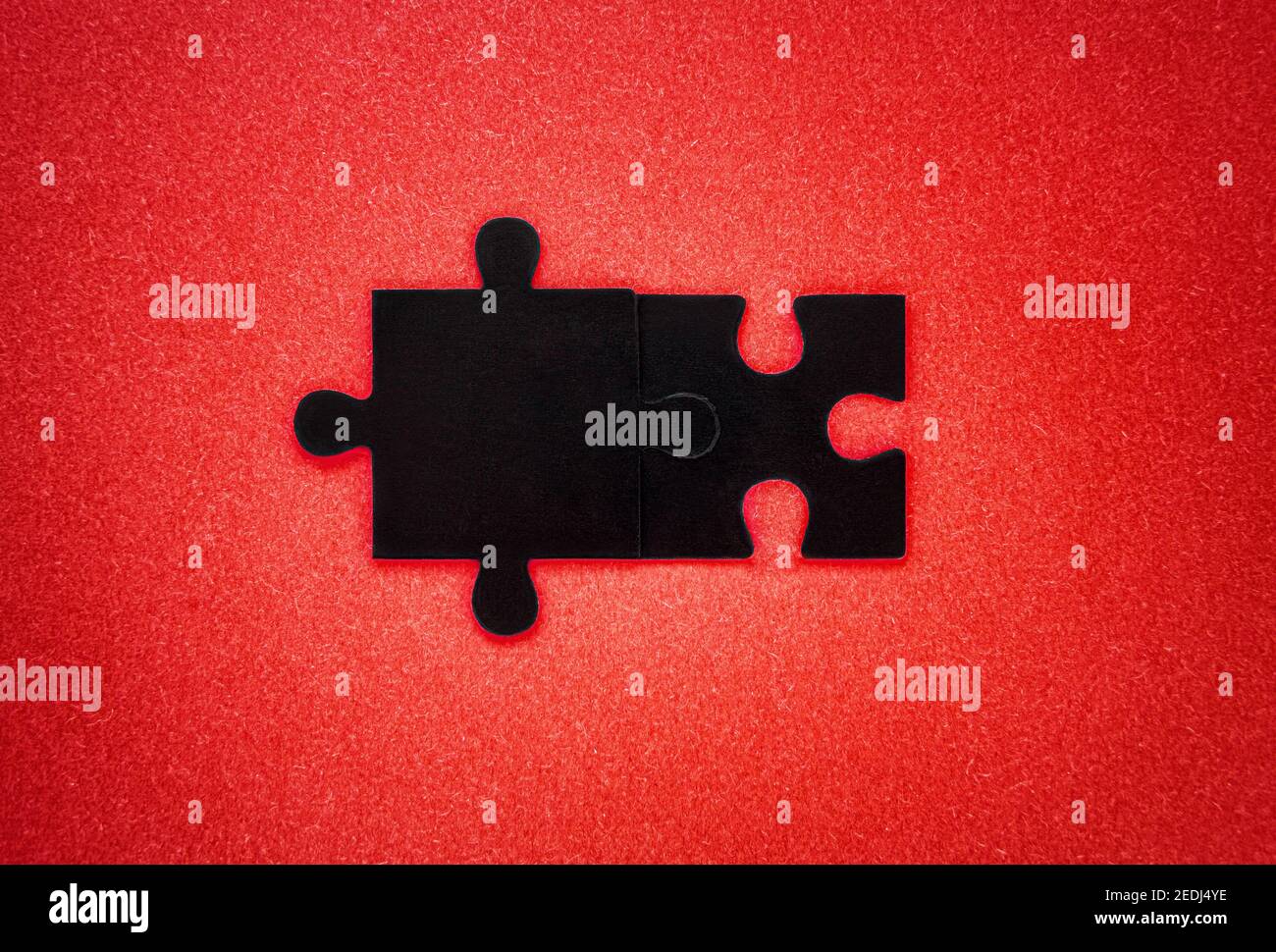 Nahaufnahme von zwei schwarzen Puzzleteilen Auf einem roten Hintergrund Stockfoto