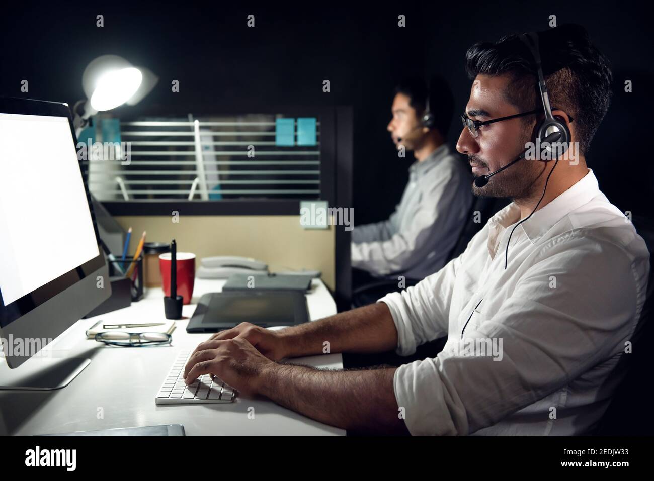 Männlicher asiatischer Kundendienst-Telemarketing-Agent, der Nachtschicht eingeht Callcenter-Büro Stockfoto