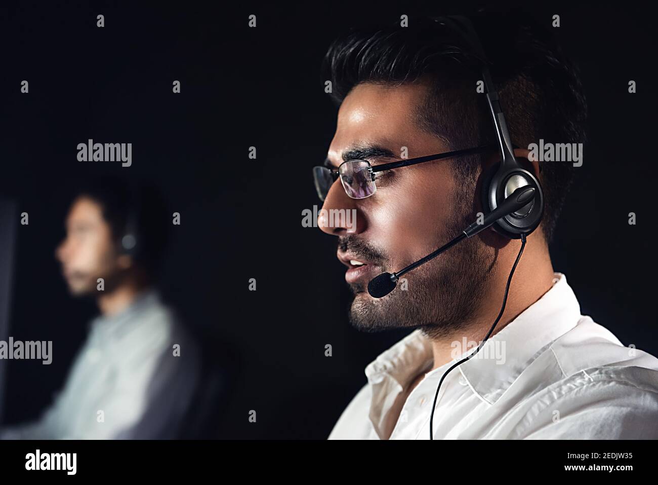 Männliche asiatische Kundenbetreuungsunternehmen, die in der Nachtschicht im Gespräch arbeiten Zentrieren Stockfoto