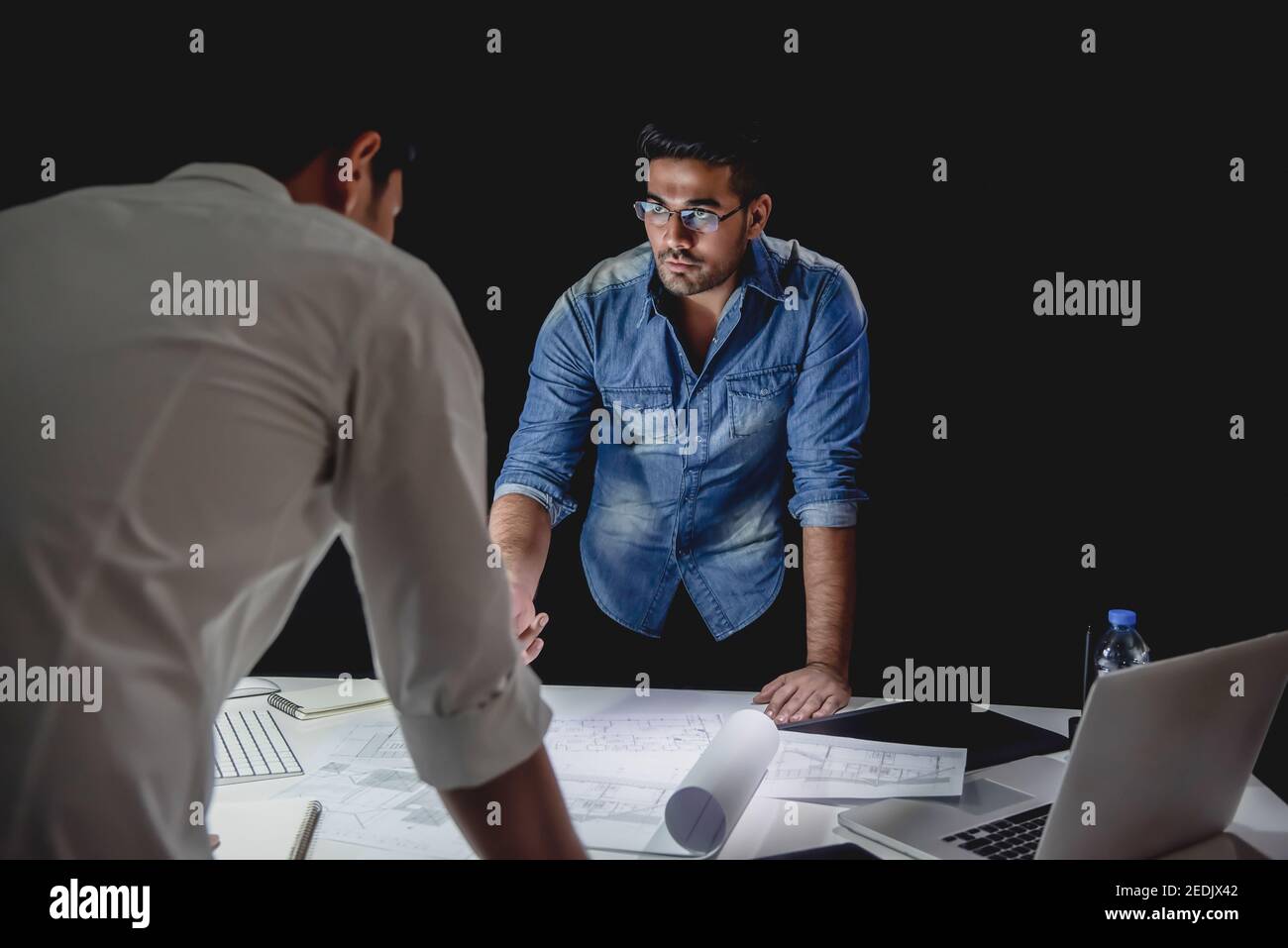 Asiatisches Architektenteam, das spät in der Nacht im Büro bleibt und diskutiert Grundriss Design-Projekt am Besprechungstisch Stockfoto