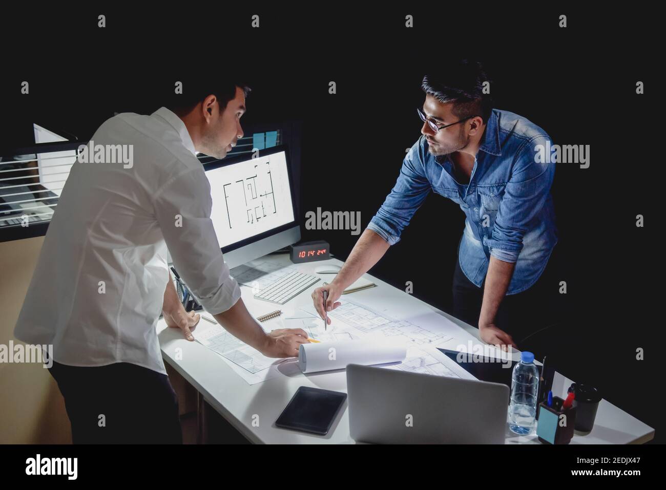 Asiatisches Architektenteam, das spät in der Nacht im Büro bleibt und diskutiert Grundriss Design-Projekt am Besprechungstisch Stockfoto