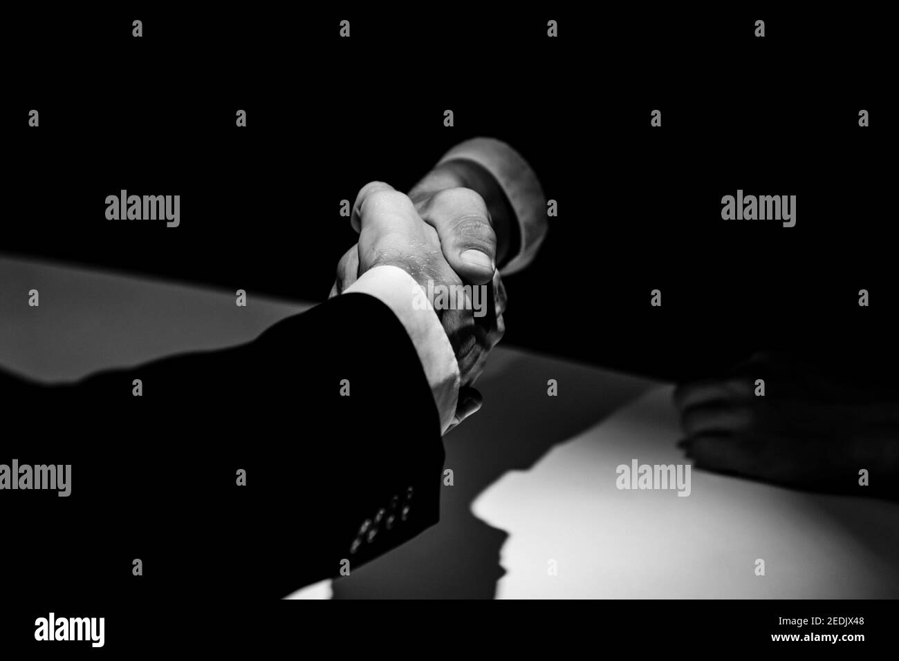 Schwarz-Weiß-Ton von anonymen Geschäftspartnern machen Handshake Im dunklen Schatten Stockfoto