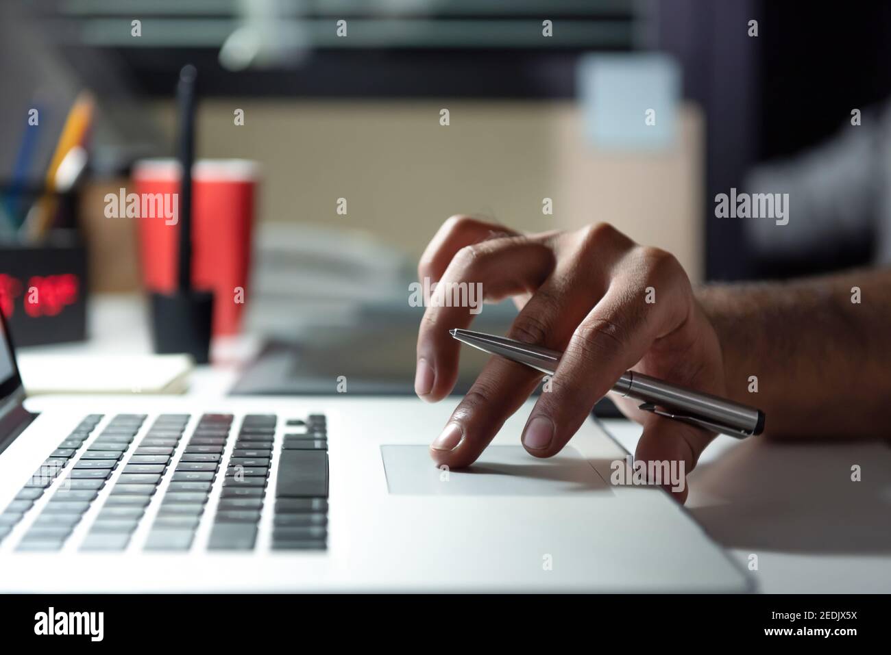 Hand eines Mannes mit Laptop-Computer arbeitet Überstunden spät Nachts im Büro an seinem Schreibtisch Stockfoto