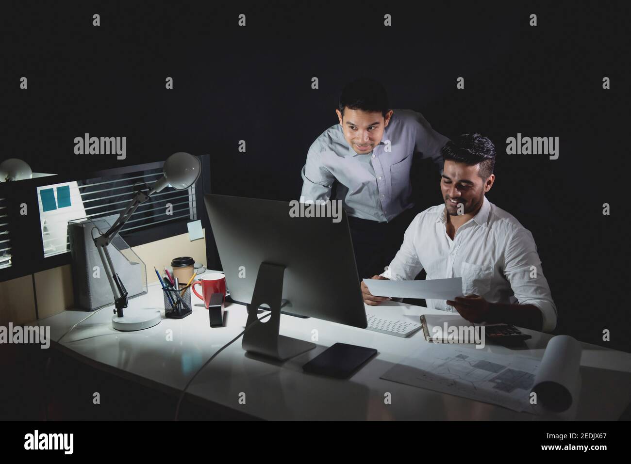 Asiatisches Architektenteam, das spät in der Nacht im Büro bleibt und diskutiert Projekt am Tisch Stockfoto