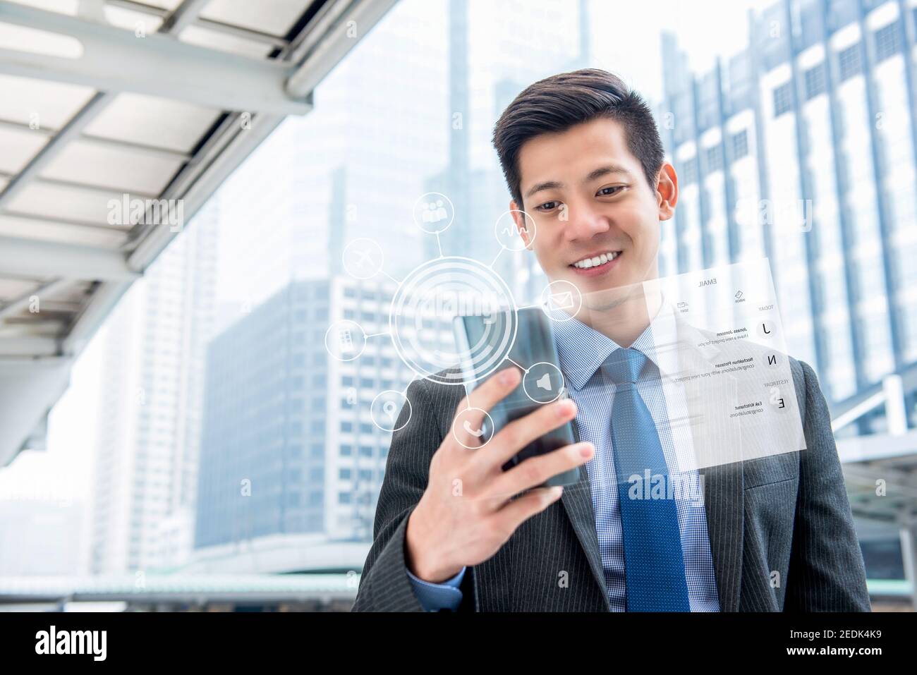 Junge gut aussehende asiatische Geschäftsmann mit Smartphone im Freien mit virtuellen digitalen Schnittstelle mit Bildschirm- und Anwendungssymbolen Stockfoto