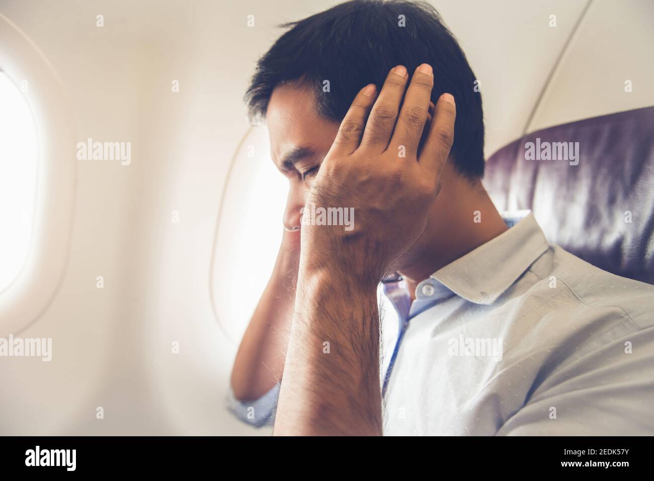 Männlicher Beifahrer mit Ohrstöpsel im Flugzeug während der Einnahme Aus (oder Landung) Stockfoto