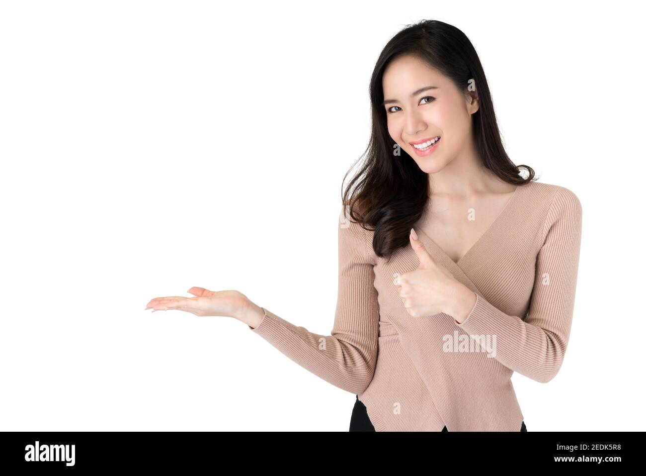 Schöne junge beiläufige asiatische Frau tut Daumen nach oben und Opean Handgesten mit leerem Raum beiseite isoliert auf weißem Hintergrund Stockfoto