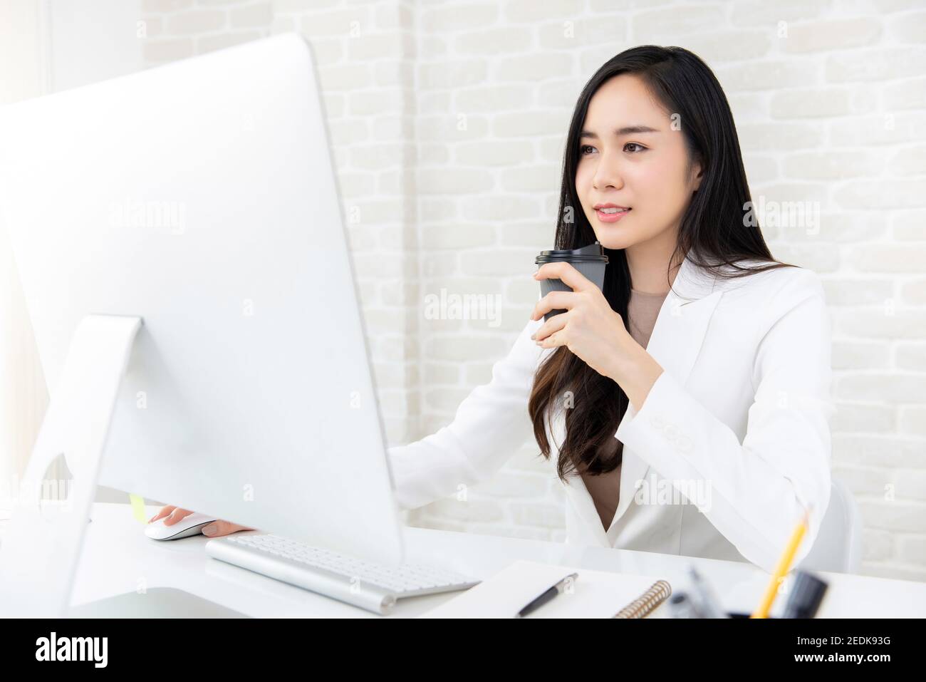 Junge schöne asiatische Frau Kaffee trinken, während mit Computer an Arbeiten Sie morgens Stockfoto