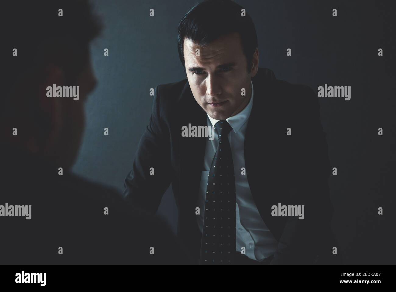 Detective interviewing Verdächtigen oder kriminellen Mann im Verhörraum Stockfoto