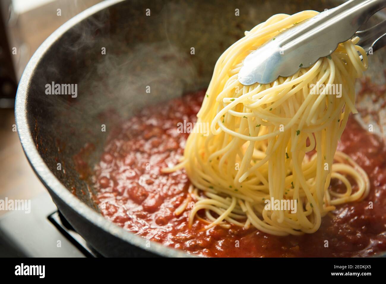 Gekochte italienische Spaghetti, die in die Pfanne mit heißen Rote Bolognese-Sauce Stockfoto