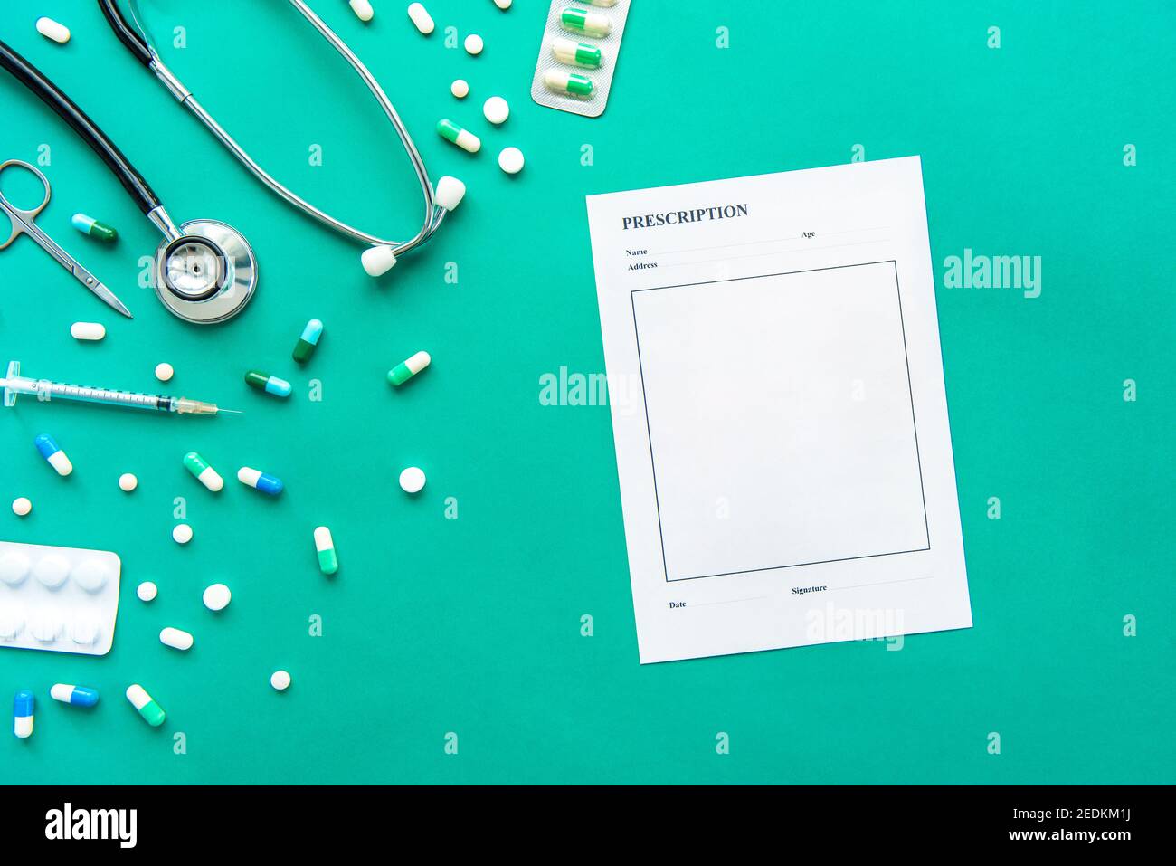 Medikamente und medizinische Instrumente wie Stethoskop, Spritze, Schere und leeres Rezepturpapier auf grünem Hintergrund Stockfoto