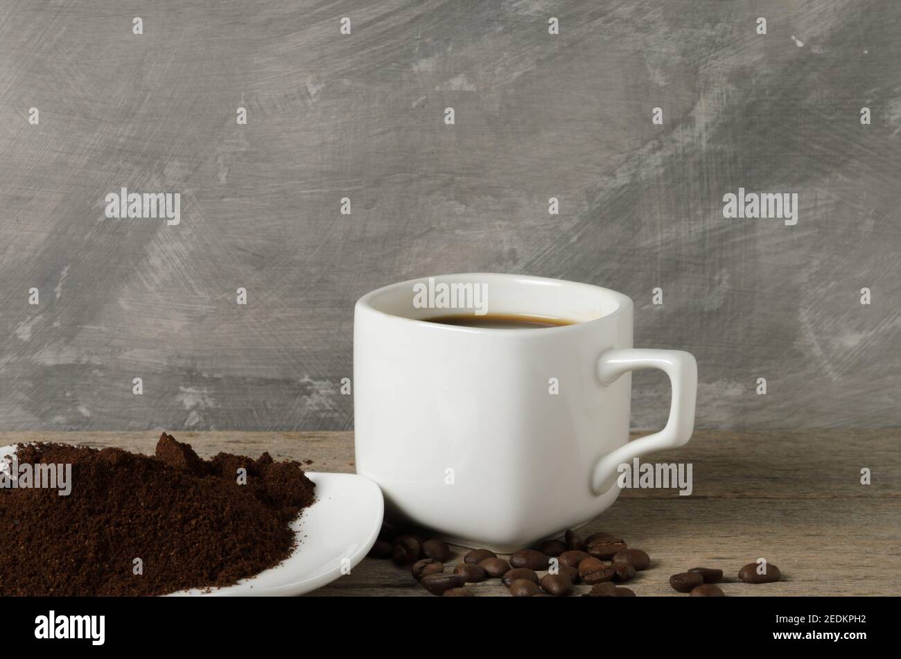 Eine Tasse Kaffee mit Kaffeebohnen und gemahlenem Kaffee auf einer Untertasse. Selektiver Fokus. Stockfoto