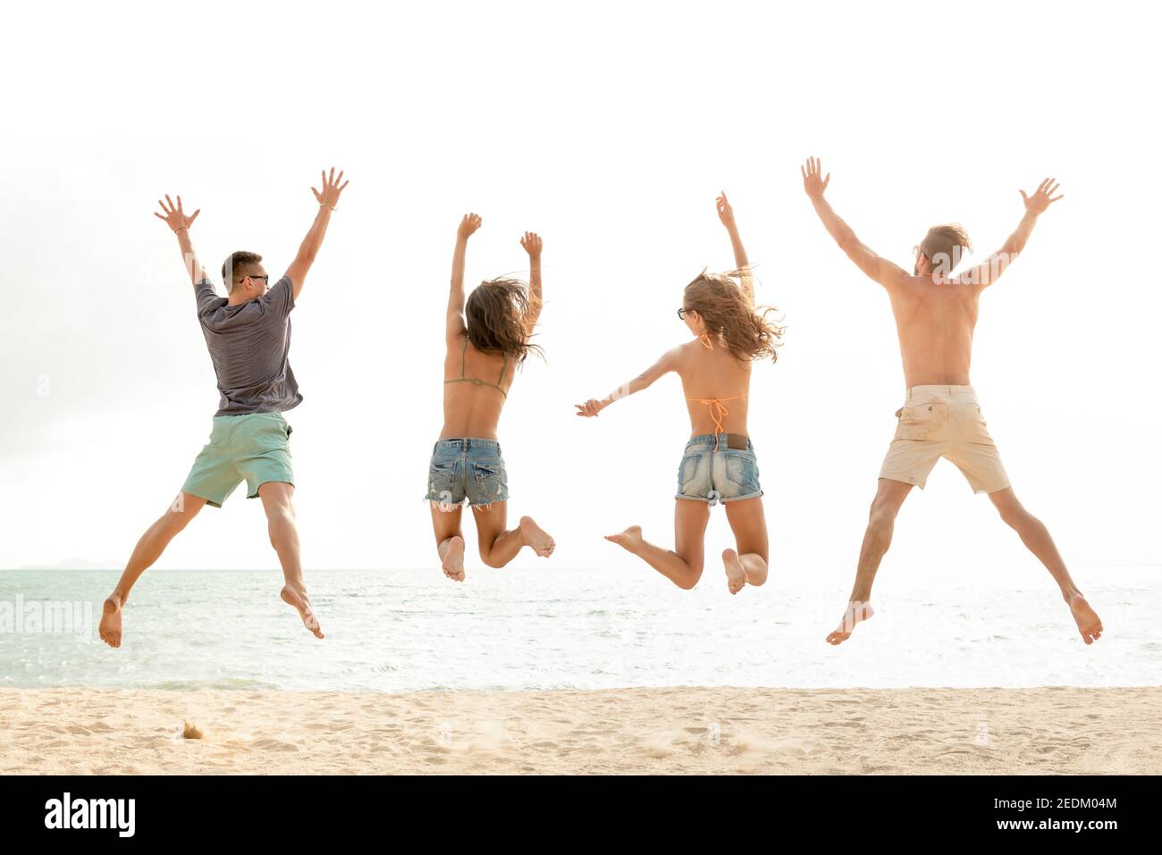 Glückliche junge energetische Gruppe von Freunden springen am Strand in den Sommerferien, Spaß und Freiheit Konzepte Stockfoto