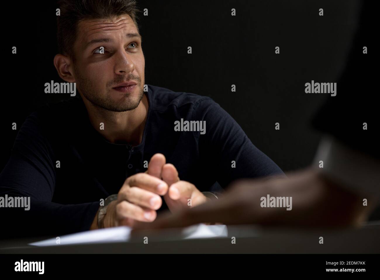 Verdächtiger oder krimineller Mann mit Handschellen, der vom Offizier interviewt wird Im Verhörraum Stockfoto