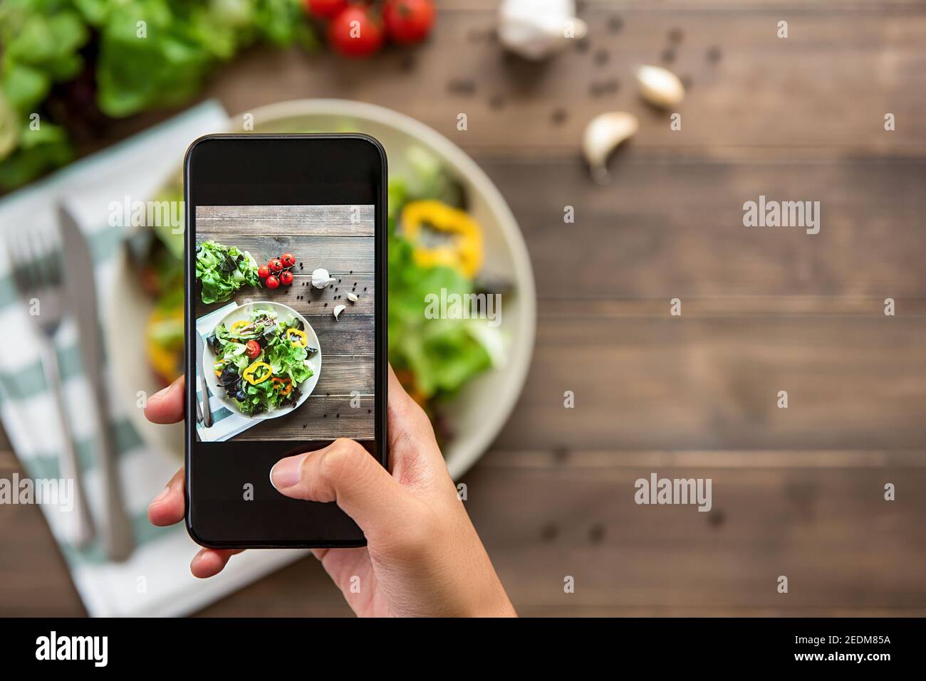 Food-Blogger mit Smartphone Foto von schönen Mix frisch Grüner Salat auf Holztisch zum Teilen in den sozialen Medien Stockfoto