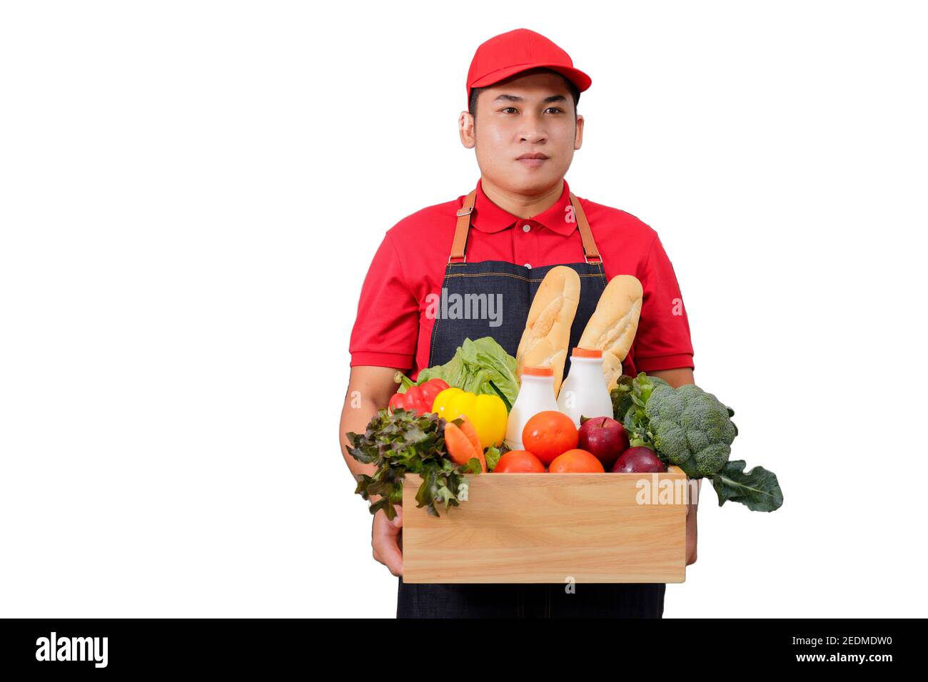 Lebensmittelgeschäft Lieferung Kurier Mann in roter Uniform mit Lebensmittelkarton mit Lebensmitteln, frischem Obst und Gemüse. Liefern Mann in roter Uniform und Schürze Handling Woode Stockfoto