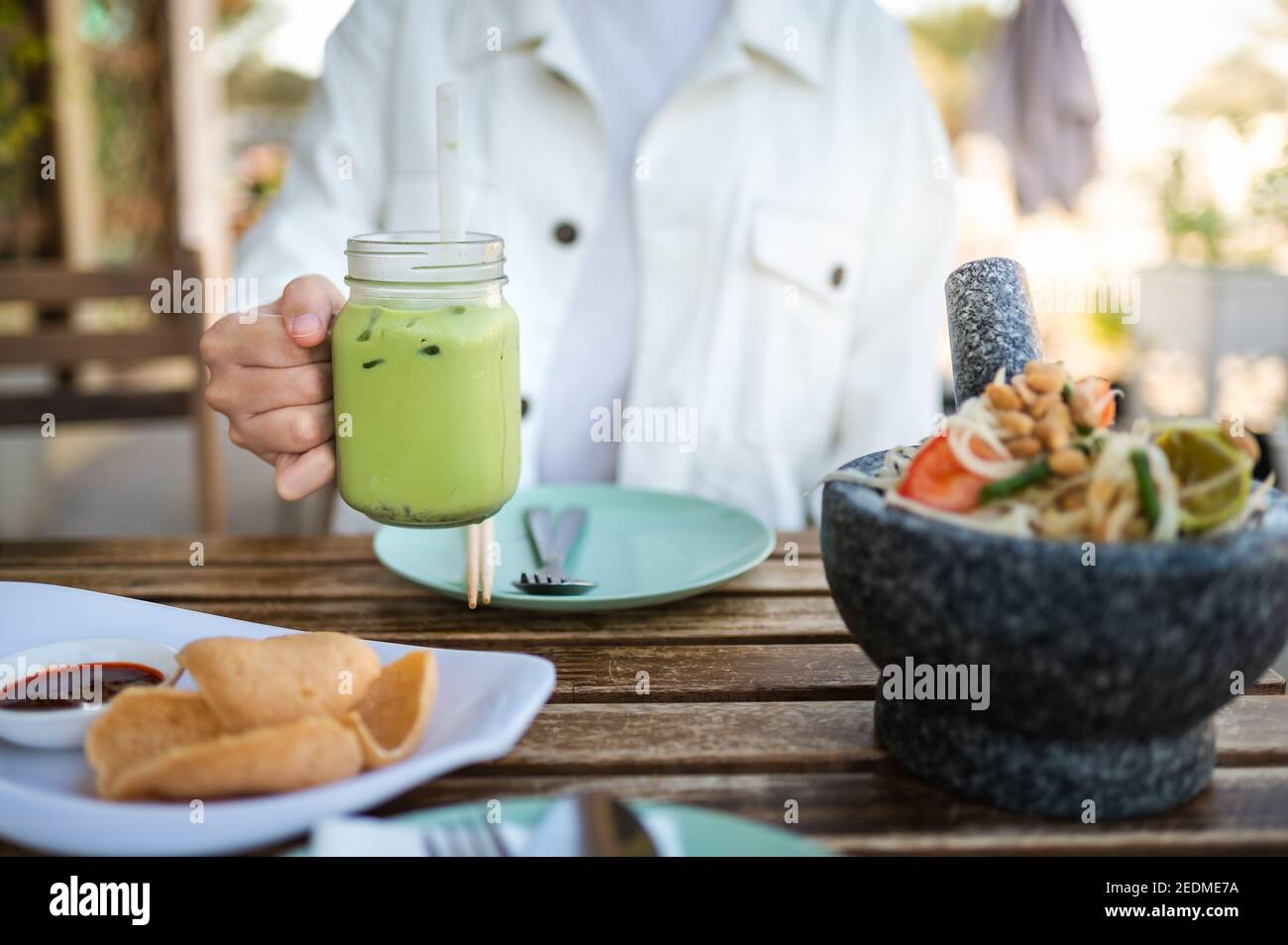 Frau mit grünem Tee während einer Mahlzeit in einem Thai Restaurant in der Nähe Stockfoto
