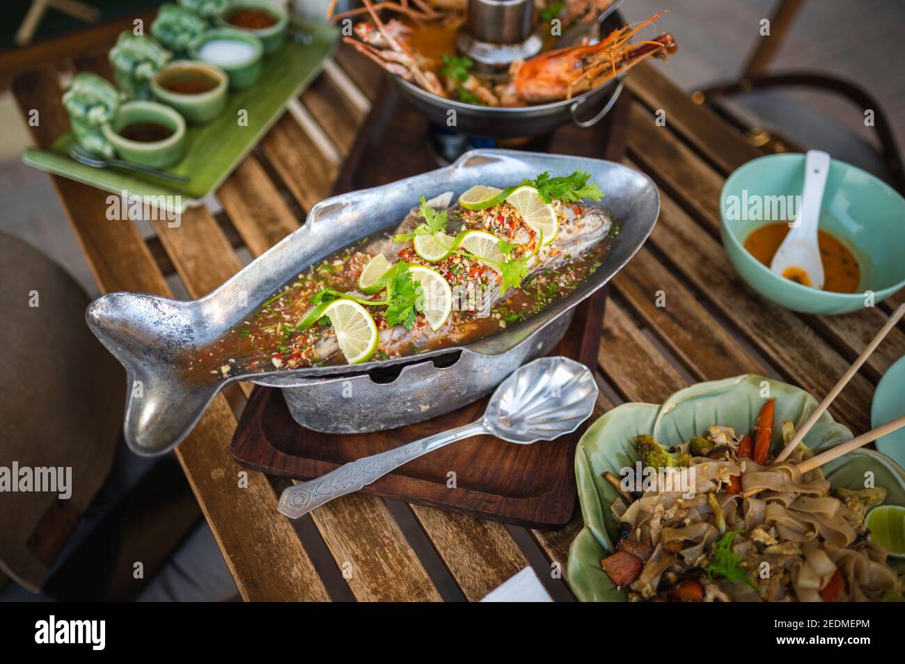 Gedünsteter Fisch mit Limettenpfeffer und verschiedenen Lebensmittelzutaten hämmern Auf einem Tisch mit thailändischen Gerichten Stockfoto
