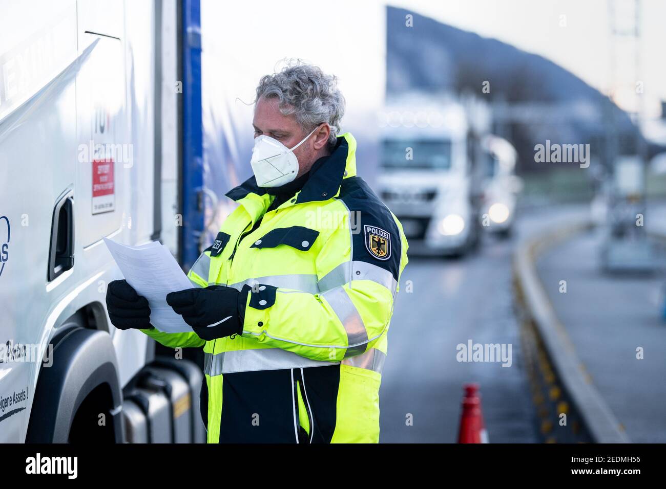 Kiefersfelden, Deutschland. Februar 2021, 15th. Ein Bundespolizist prüft die Dokumente eines Lastwagenfahrers, der aus Österreich auf der Autobahn A93 bei Kiefersfelden in Richtung Deutschland kommt. Die verschärften deutschen Einreisebestimmungen an der Grenze zum österreichischen Bundesland Tirol zum Schutz vor gefährlichen Varianten des Coronavirus sind am Sonntagabend in Kraft getreten. Quelle: Matthias Balk/dpa/Alamy Live News Stockfoto