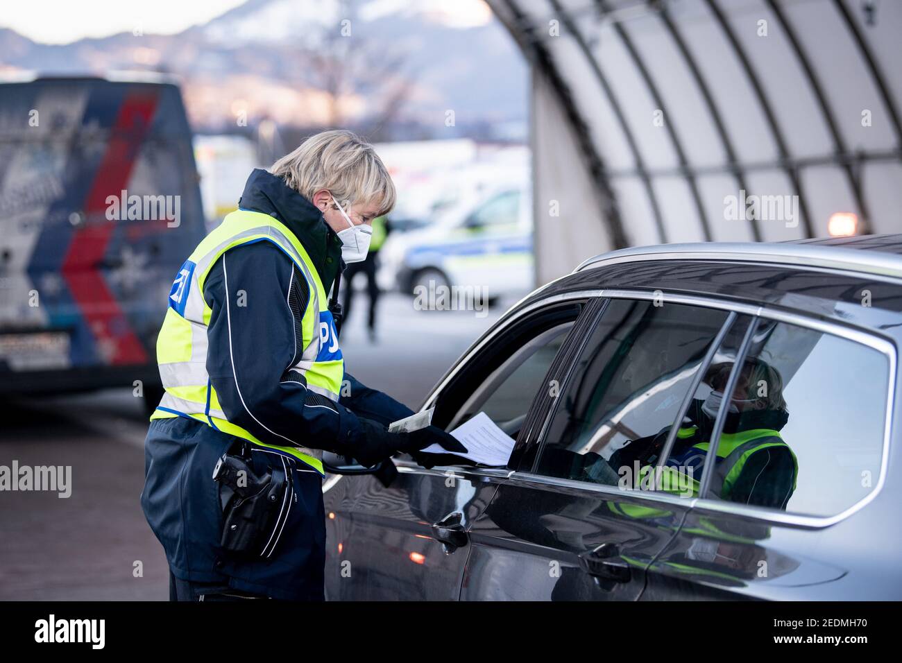 Kiefersfelden, Deutschland. Februar 2021, 15th. Ein Bundespolizist überprüft die Dokumente eines Reisenden aus Österreich an einem Kontrollpunkt auf der Autobahn A93 bei Kiefersfelden in Richtung Deutschland. Die verschärften deutschen Einreisebestimmungen an der Grenze zum österreichischen Bundesland Tirol zum Schutz vor gefährlichen Varianten des Coronavirus sind am Sonntagabend in Kraft getreten. Quelle: Matthias Balk/dpa/Alamy Live News Stockfoto