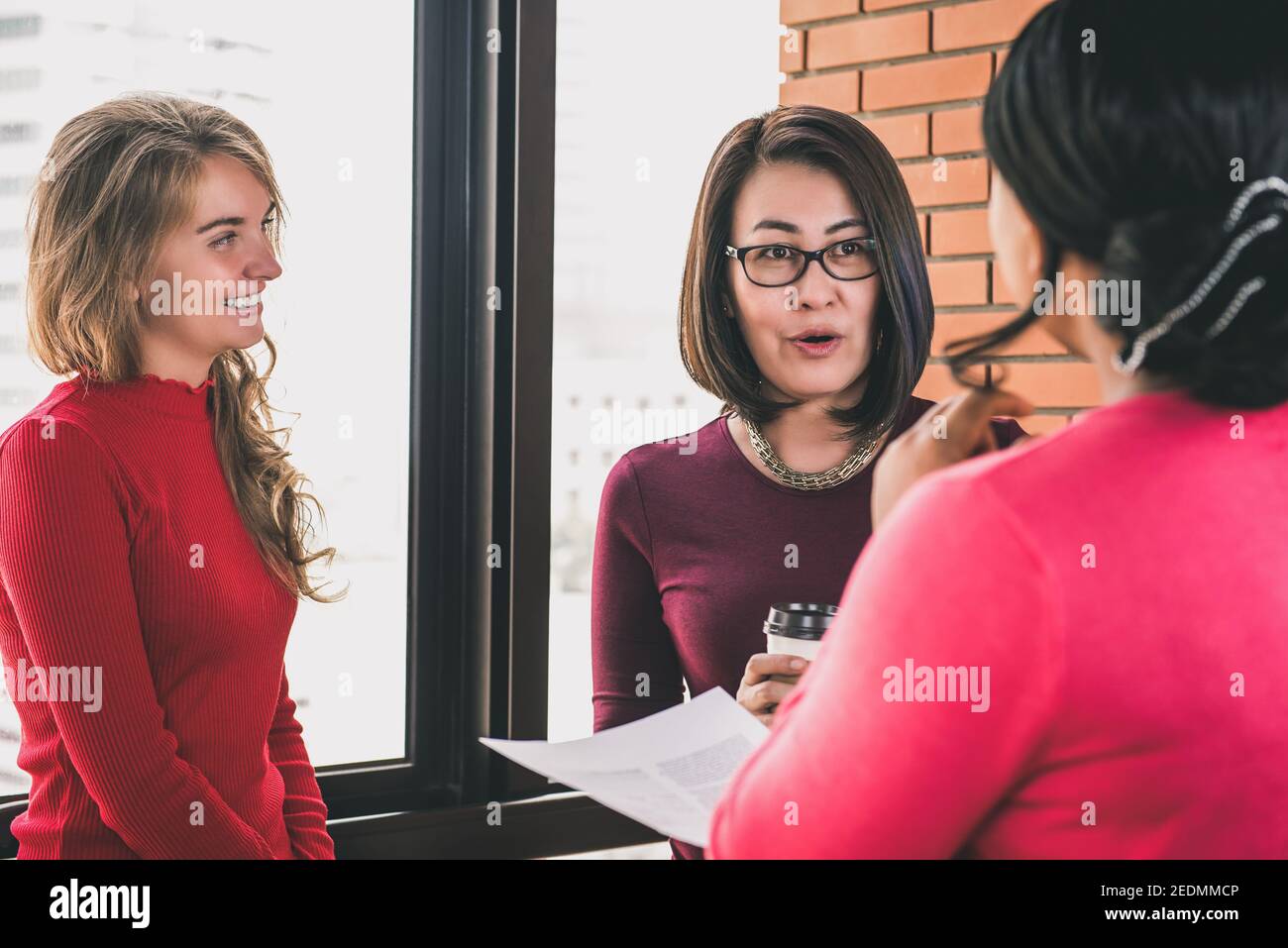 Gruppe von mächtigen verschiedenen Frauen in lässiger Kleidung standing und Diskutieren in Co-Working Büroräume Stockfoto