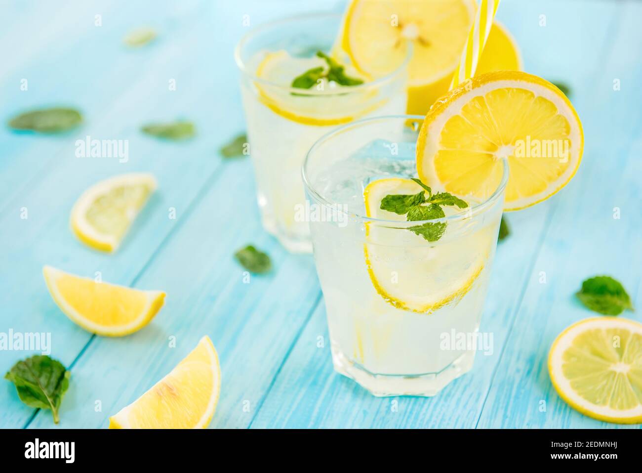 Erfrischende Getränke für den Sommer, kalter süßer und saurer Limonensaft mit Eiswürfeln in den Gläsern garniert mit frisch geschnittenen Zitronen Stockfoto