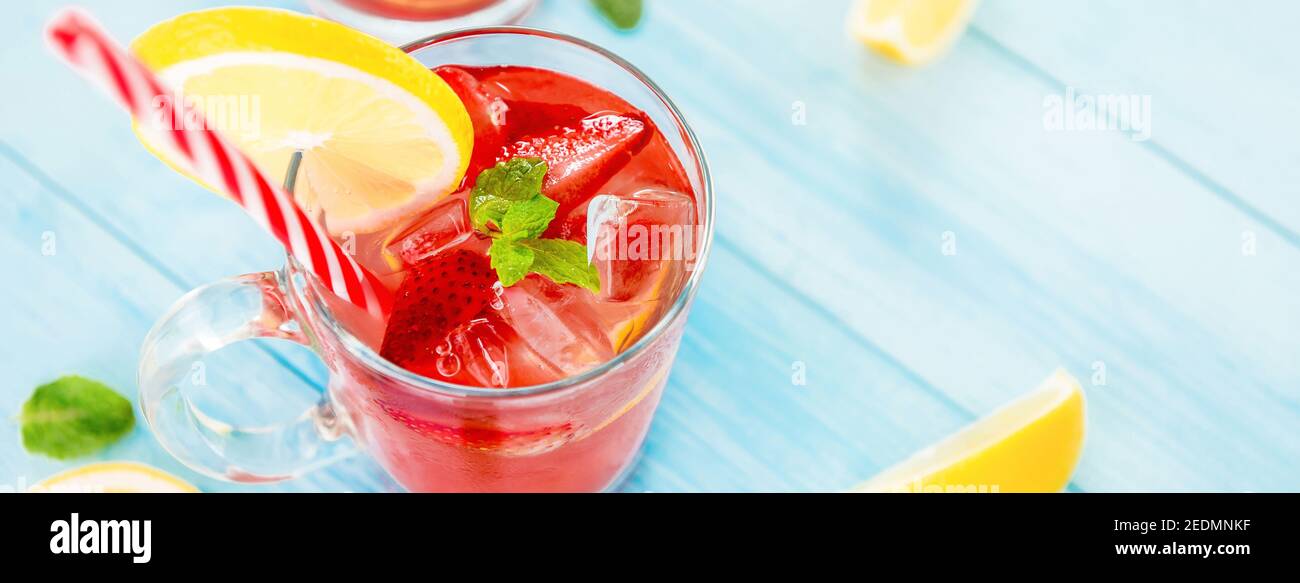 Bunte Erfrischungsgetränke für den Sommer, kalter Erdbeer-Limonensaft mit Eiswürfeln in der Glasse garniert mit frisch geschnittener Zitrone Stockfoto