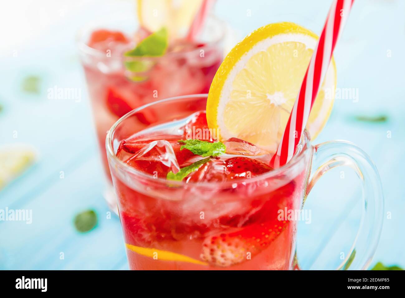 Bunte Erfrischungsgetränke für den Sommer, kalter Erdbeer-Limonensaft mit Eiswürfeln in den Gläsern garniert mit frisch geschnittenen Zitronen Stockfoto