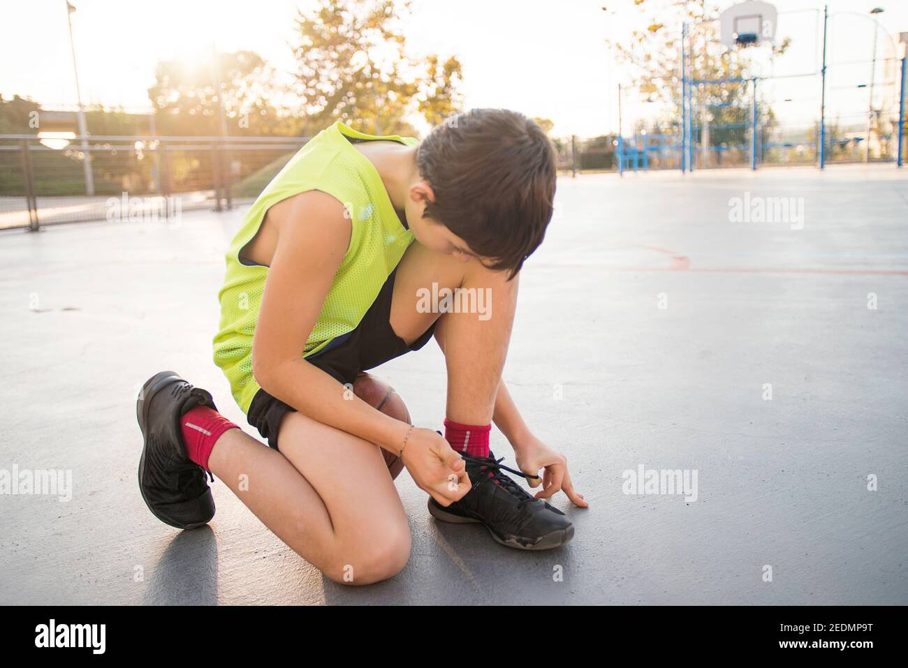 Der junge Basketballspieler bindet Schnürsenkel Stockfoto