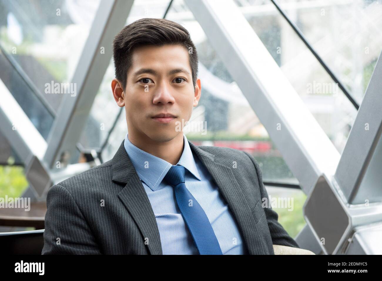 Junger, kräftiger, gutaussehender, asiatisch-thailändischer Geschäftsmann sitzt in der Bürolounge Stockfoto