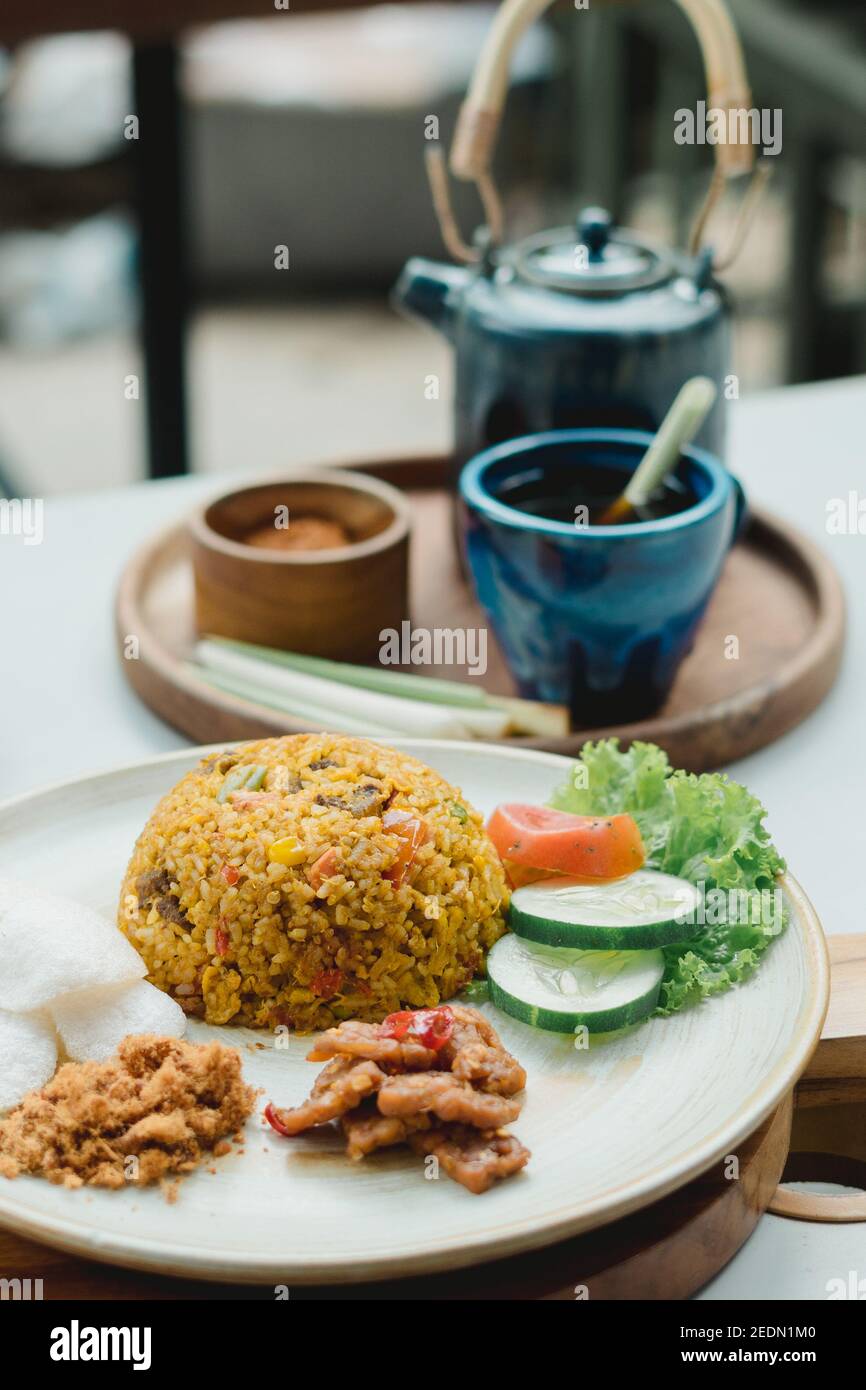 Indonesiann nasi goreng oder gebratener Reis mit Gemüse und Sauce sambal serviert mit Töpferwaren Zubehör Stockfoto