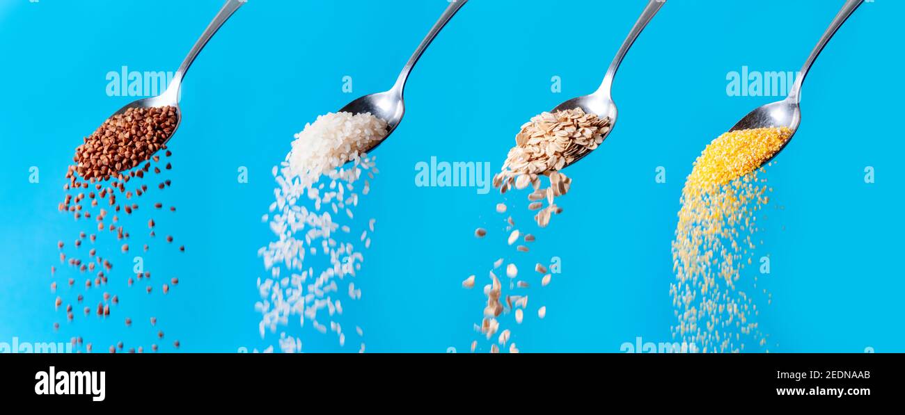 Mischen Sie Bio-Getreidekörner. RAW Buchweizen Samen, Haferflocken, Reis, Mais Körner Flocken fallen aus Löffel auf blauem Hintergrund. Stockfoto