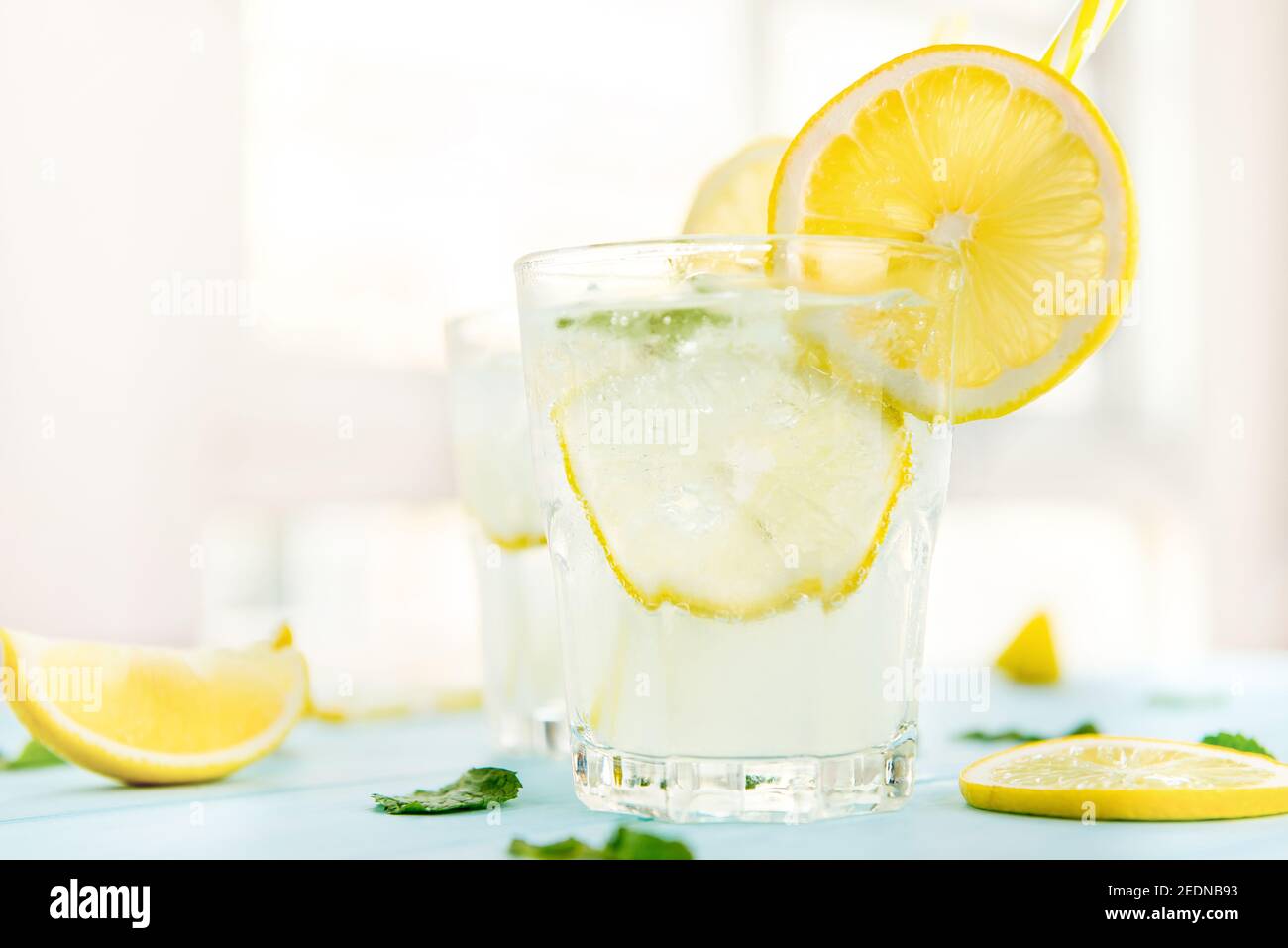 Erfrischende Getränke für den Sommer, kalter süß-saurer Limonensaft mit Eiswürfeln in den Gläsern garnieren mit Zitronenscheiben Stockfoto