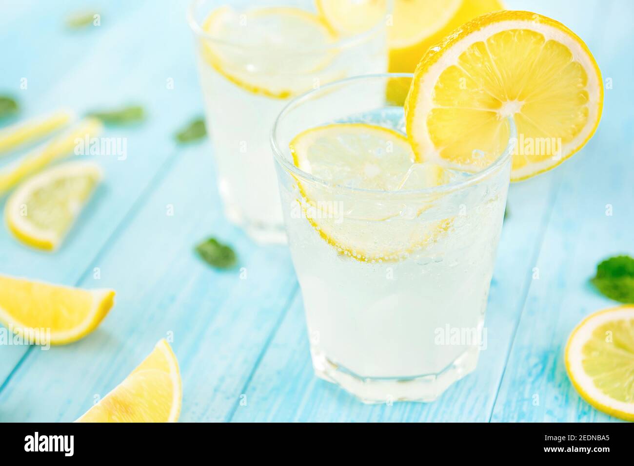 Erfrischende Getränke für den Sommer, kalter süßer und saurer Limonensaft mit Eiswürfeln in den Gläsern garniert mit Zitronenscheiben Stockfoto