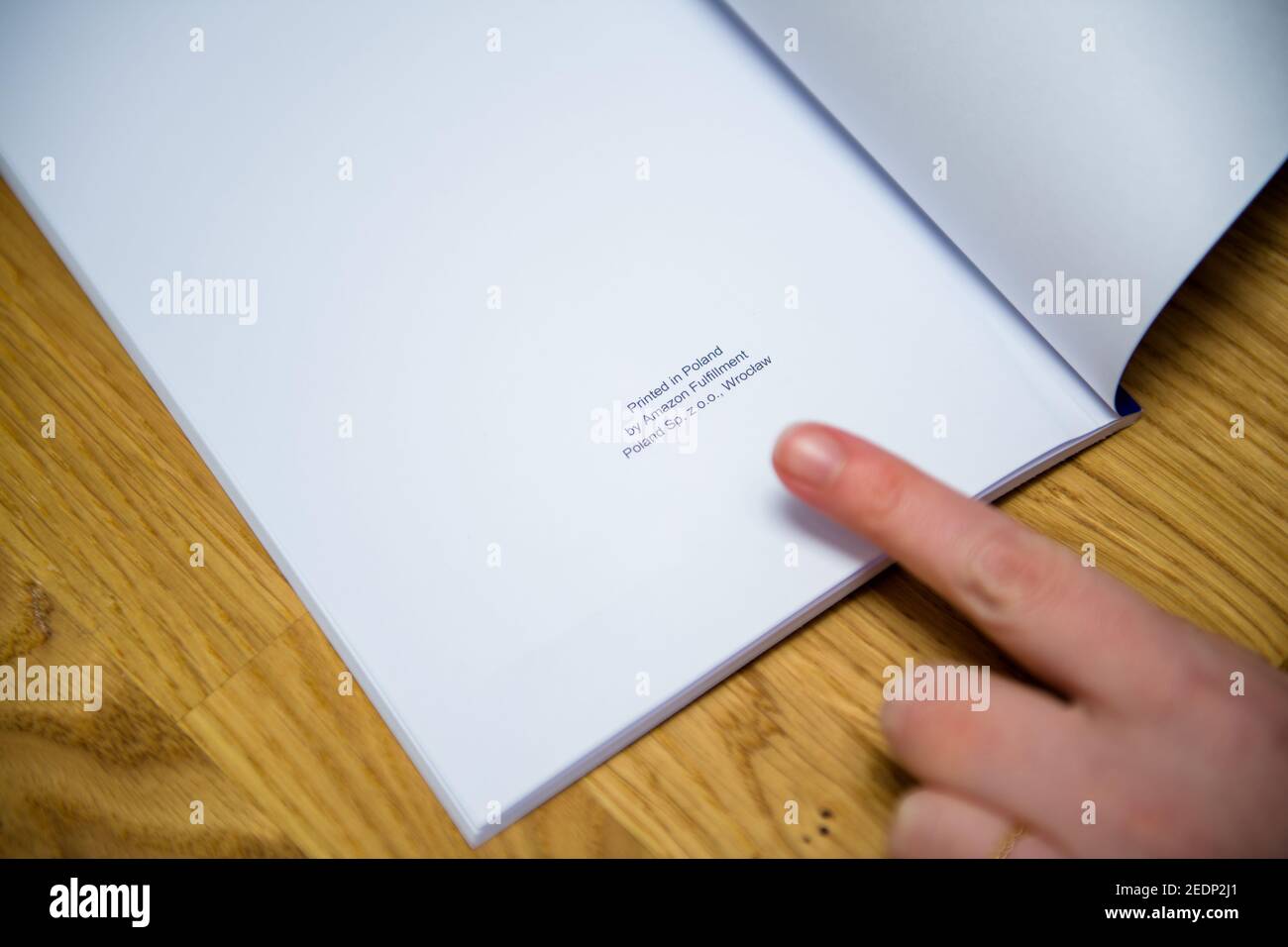 Paris, Frankreich - 14. Feb 2021: POV Frau zeigt mit dem Finger den Text am Ende des Buches gedruckt in Polen von Amazon Versand Polen SP z oo Wroclaw - Self Publishing Buch Stockfoto