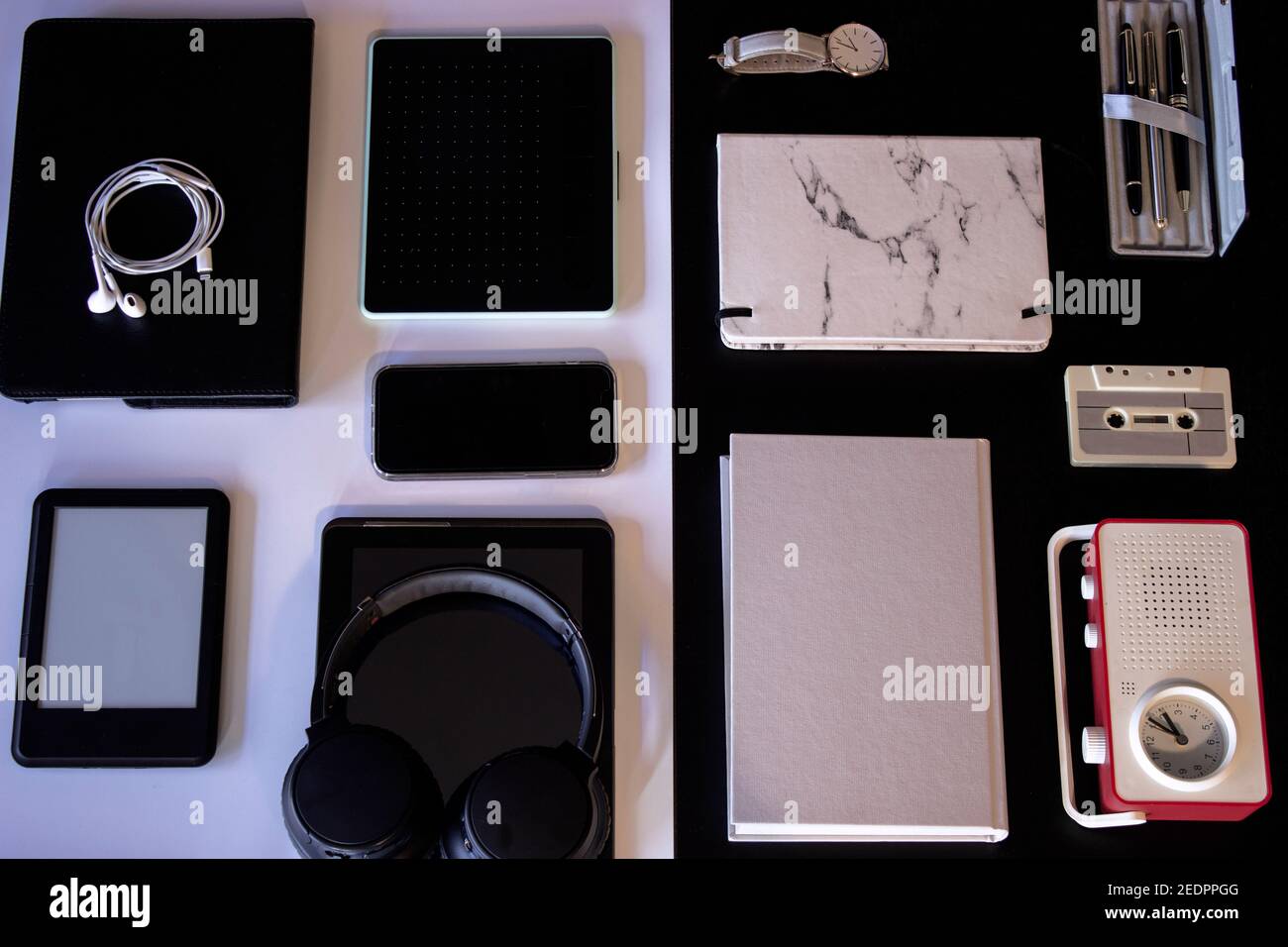 Top View Kopfhörer, E-Book, Grafik-Tablet, Laptop, Mobiltelefon, Uhr, Buch, Wecker, Stift, Buch und Stift auf S&W Hintergrund. Technologiekonzept Stockfoto
